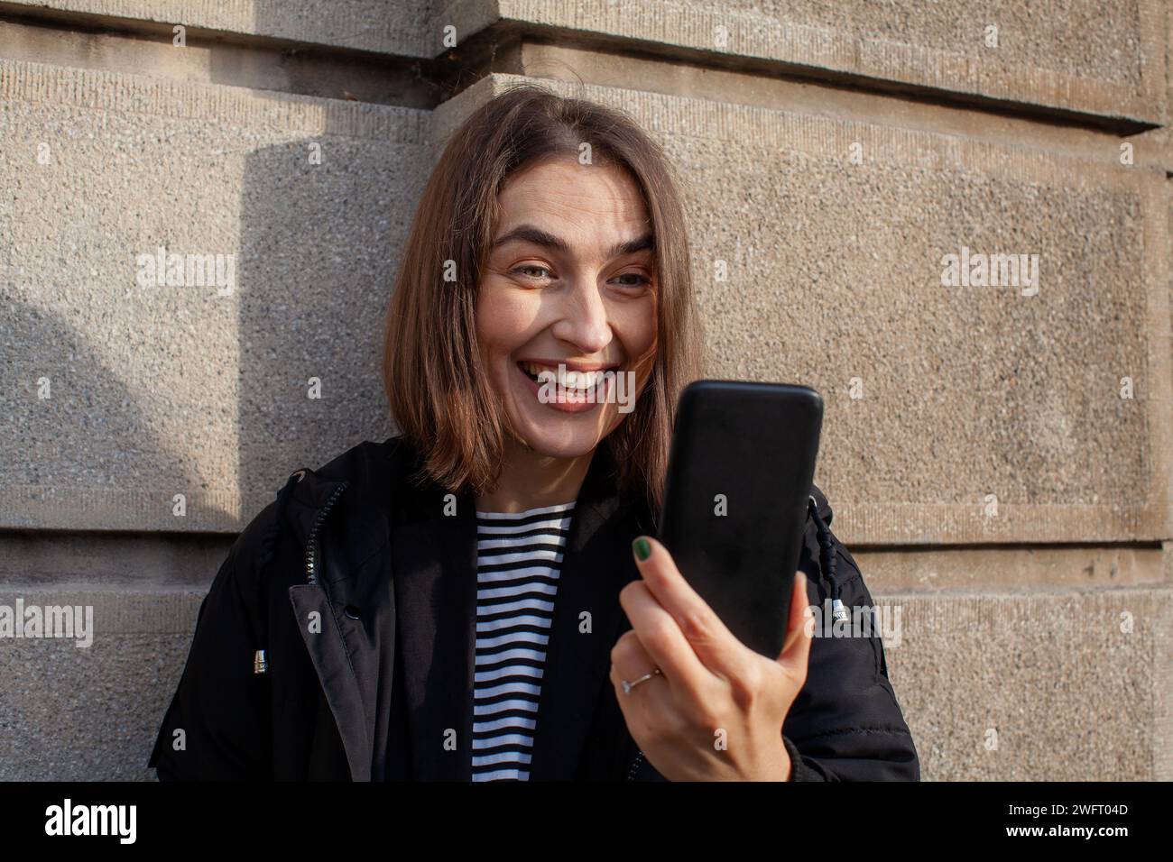 Lächelnde Frau, die ihr Smartphone ansieht Stockfoto