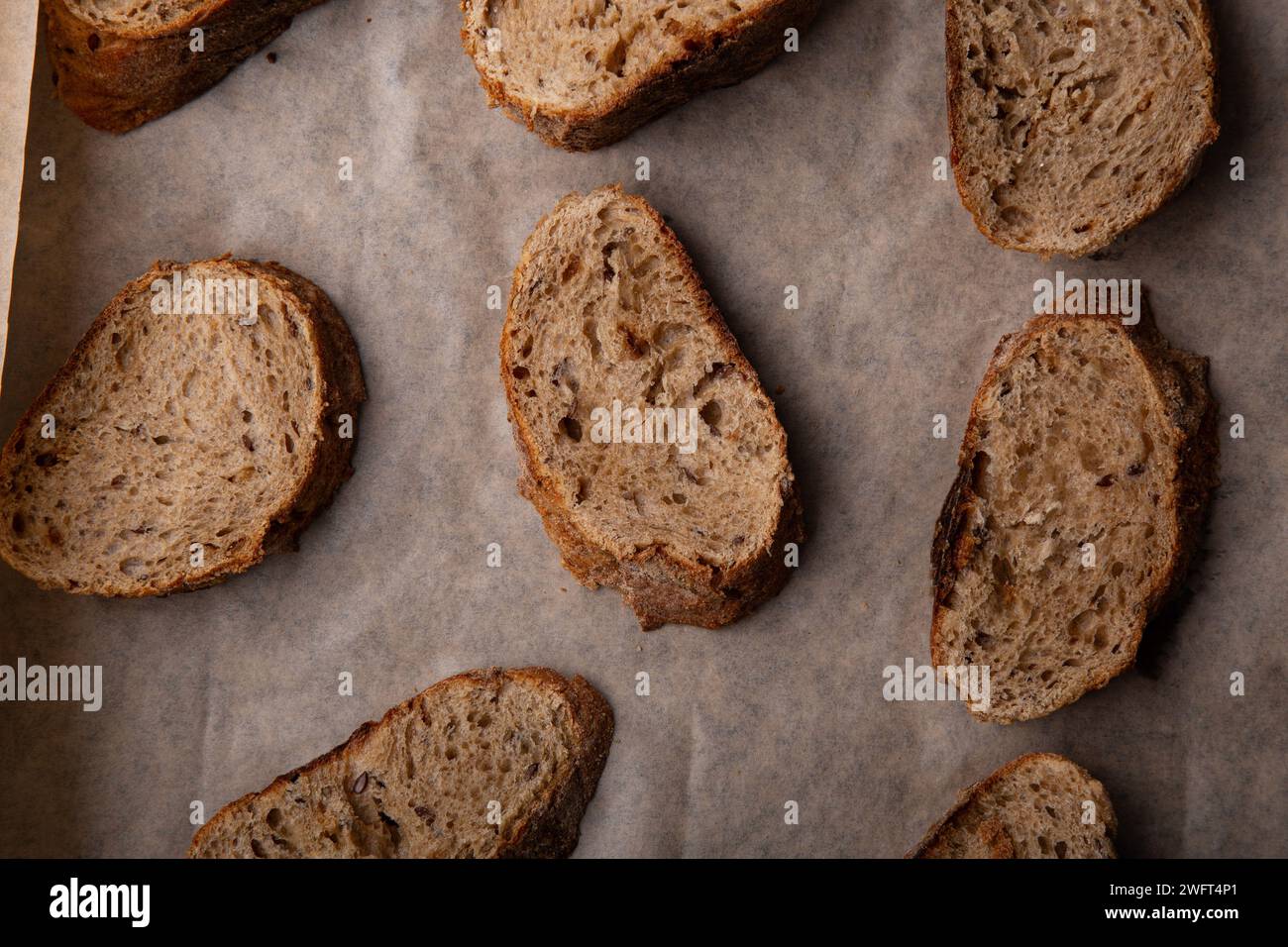 Handwerkliche Mehrkornbrotscheiben auf Backpapier. Stockfoto