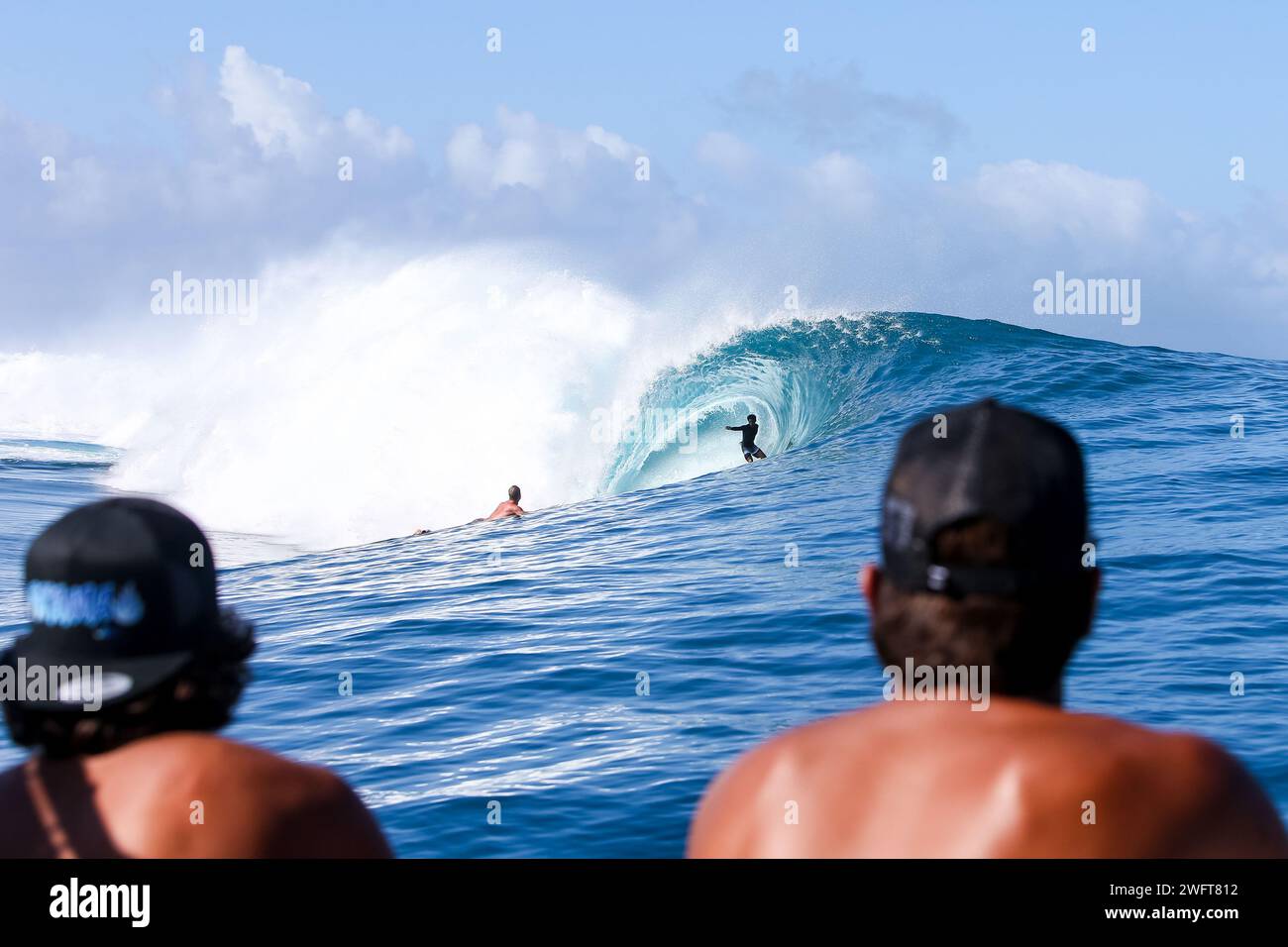 Französisch-Polynesien, Tahiti, Surfplatz in Teahupo'o: Surfer auf einem Boot, die andere Surfer beobachten, die eine Tonnenwelle surfen und mit der Tube fahren. Teahupos ist s Stockfoto