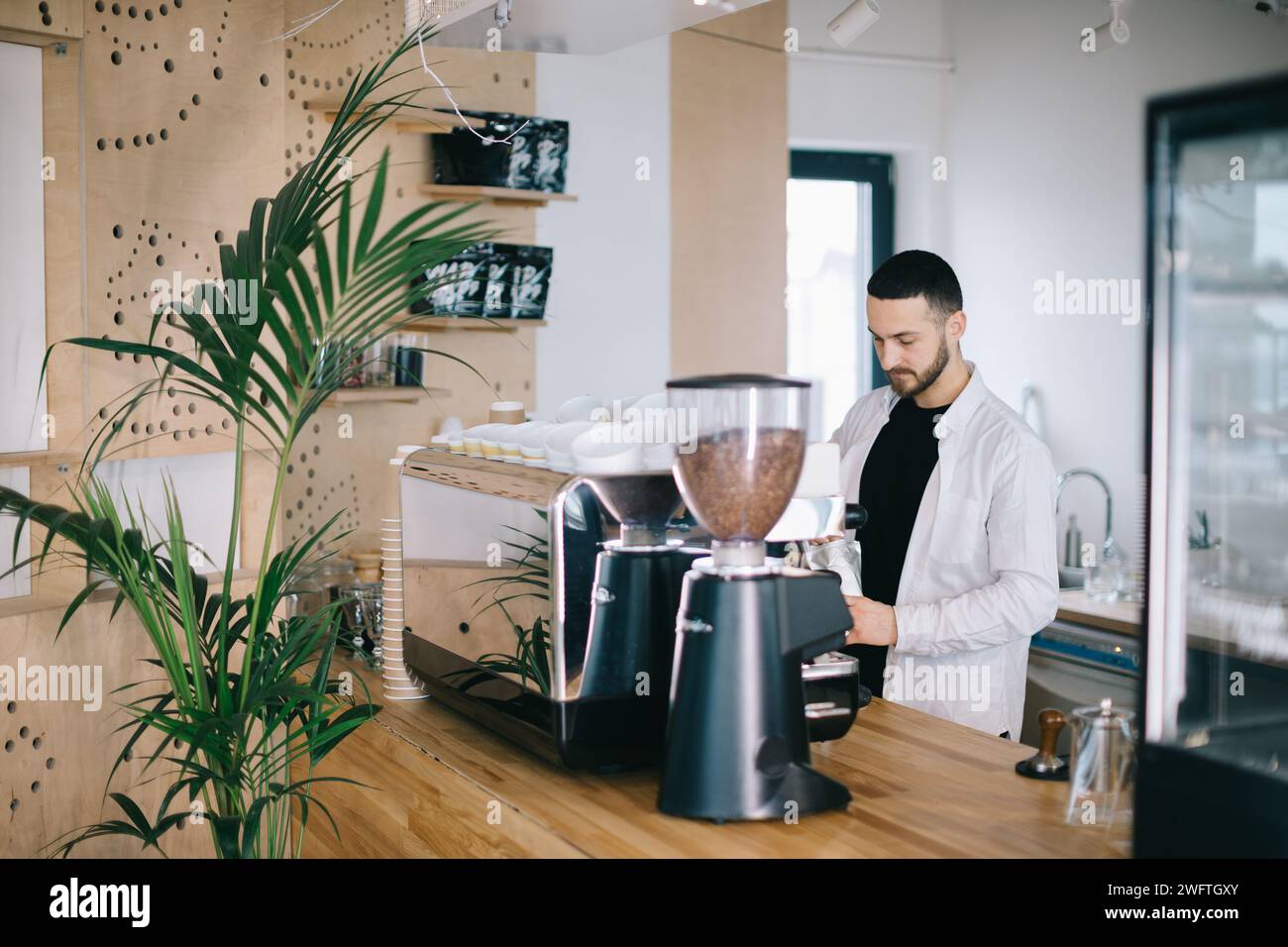 Ein Barista in der Nähe einer Espressomaschine bereitet leckeren Kaffee zu. Ein junger Mann bereitet Kaffee in einem Café zu. Stockfoto