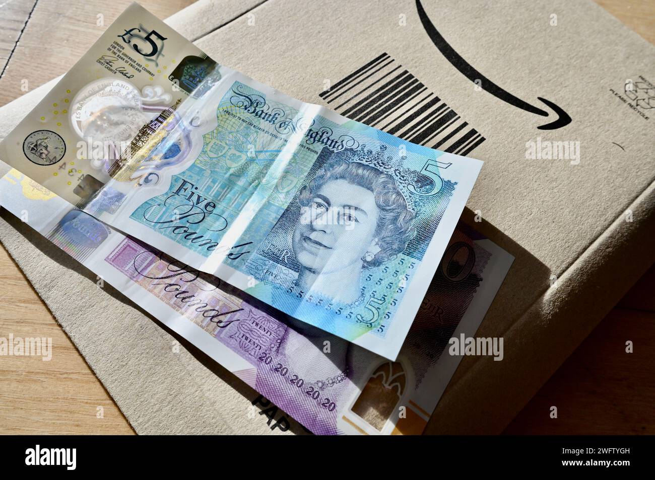 Amazon-Paket und Sterling-Bargeld (5- und 20-Pfund-Scheine). Stockfoto