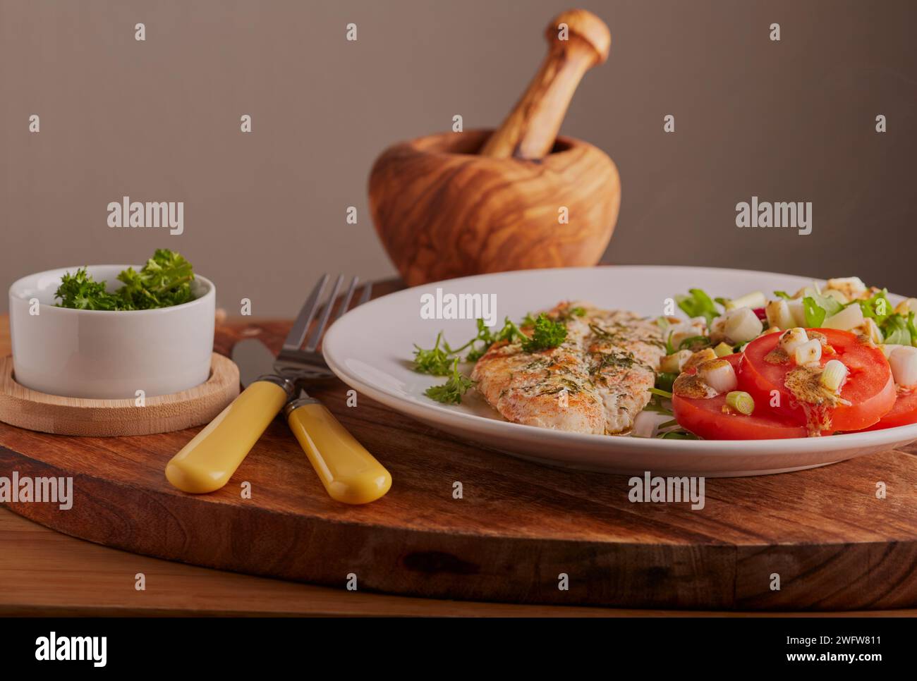 Fischfilet mit gemischtem Salat und garniert mit Salatdressing. Stockfoto