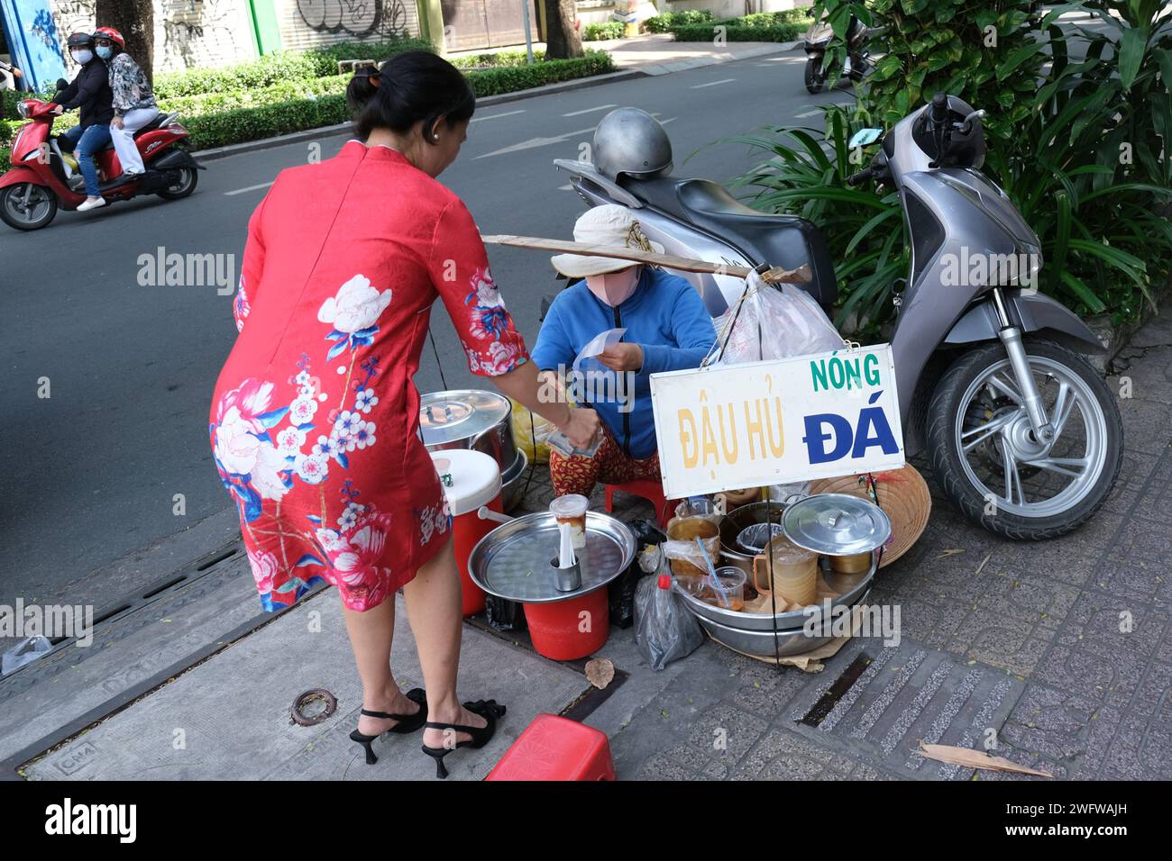 Eine Frau der Mittelklasse kauft Essen von einem Straßenverkäufer in der Innenstadt von Ho-Chi-Minh-Stadt, Vietnam Stockfoto