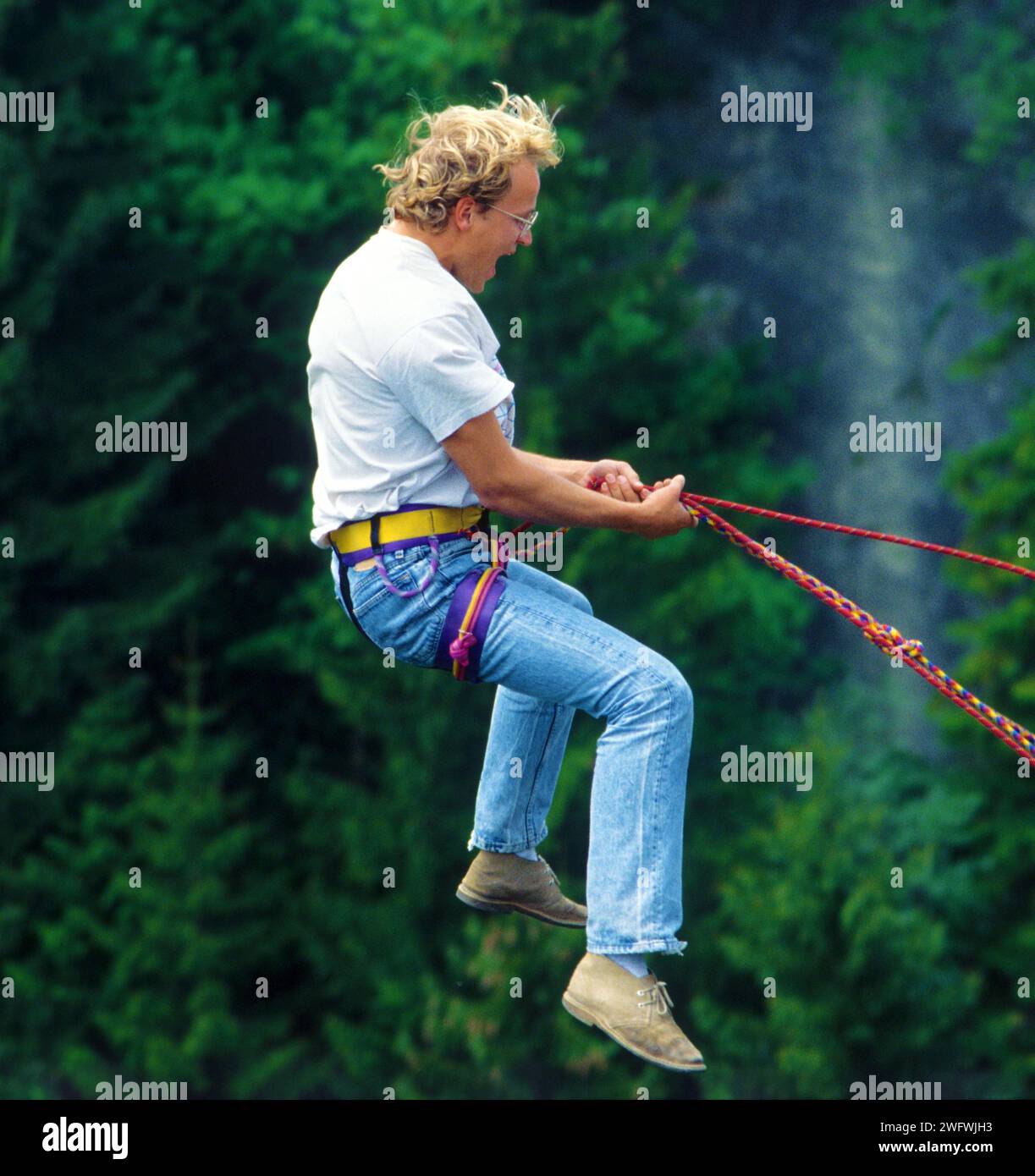 Ein junger Mann springt von einer Brücke, gesichert durch ein Seil Stockfoto