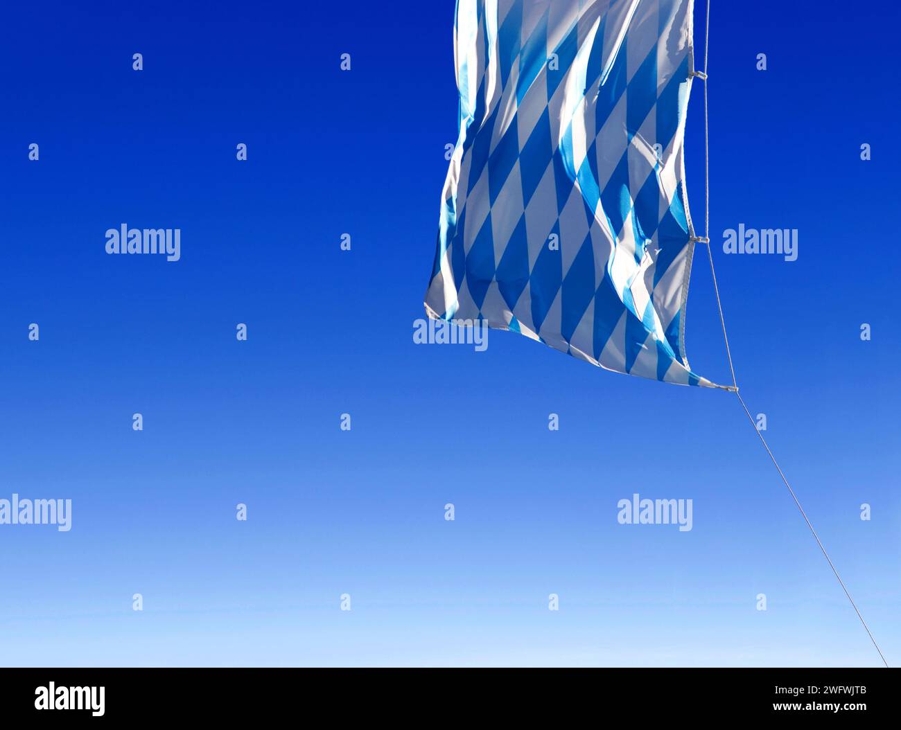 Die blauen und weißen Diamanten der bayerischen Flagge winken im Wind am blauen Himmel Stockfoto