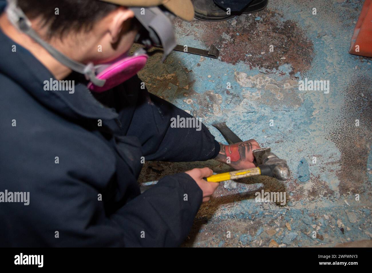 YOKOSUKA, Japan (4. Januar 2024) Fire Controlman 3rd Class Leopold Godell aus Vancouver, Washington, verwendet einen Hammer und Meißel, um Fliesen auseinander zu brechen, während er Deck-Abriss an Bord der USS Ronald Reagan (CVN 76) durchführt, während im Hafen Commander, Fleet Activities Yokosuka, 4. Januar. Ronald Reagan, das Flaggschiff der Carrier Strike Group 5, stellt eine kampfbereite Truppe zur Verfügung, die die Vereinigten Staaten schützt und verteidigt und Allianzen, Partnerschaften und kollektive maritime Interessen in der indopazifischen Region unterstützt. Stockfoto