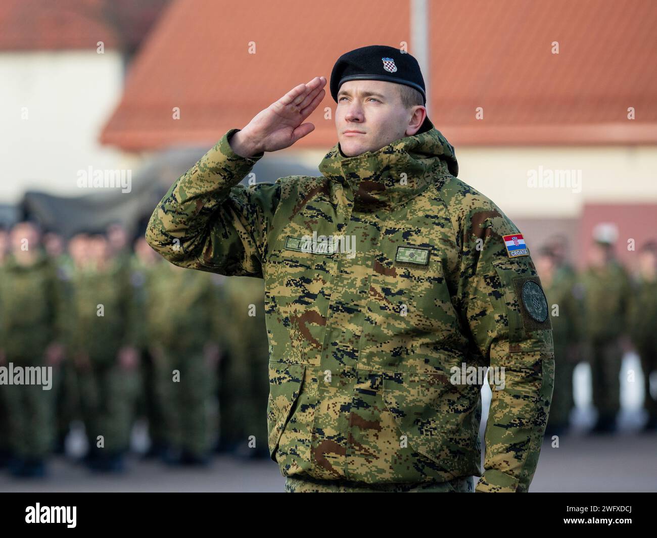 Pvt. Roberto Lukini, ein Munitionsspezialist des 12. Kroatischen Kontingents „Eiserne Eber“, der die verstärkte Präsenz der NATO-Kampfgruppe Polen unterstützt, würdigt die Flagge, während die kroatische Nationalhymne während der Übertragung der Autorität zwischen dem ausscheidenden 12. kroatischen Kontingent „Eiserne Eber“ und dem eingehenden 13. kroatischen Kontingent „Eiserne Sturm“ im Bemowo Piskie Trainingsgebiet, Polen, am 29. Januar 2024 gespielt wird. Die Mission der 3. Infanteriedivision in Europa besteht darin, sich an multinationalen Schulungen und Übungen auf dem gesamten Kontinent zu beteiligen, wobei sie mit den NATO-Verbündeten und regionalen Sicherheitskräften zusammenarbeitet Stockfoto