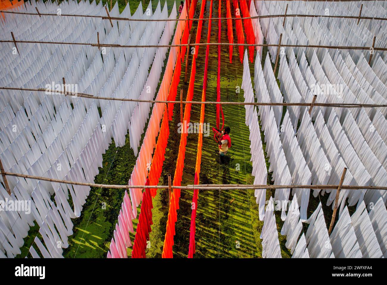 Aus der Vogelperspektive von Menschen, die in einer öffentlichen Wäscherei arbeiten, die zum Trocknen von bunten Stoffen in Narayanganj, Dhaka, Bangladesch hängend sind. Stockfoto