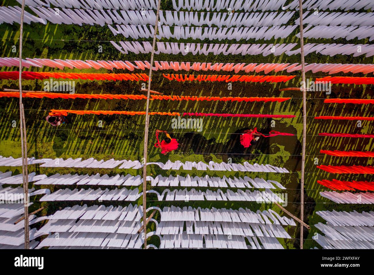 Aus der Vogelperspektive von Menschen, die in einer öffentlichen Wäscherei arbeiten, die zum Trocknen von bunten Stoffen in Narayanganj, Dhaka, Bangladesch hängend sind. Stockfoto