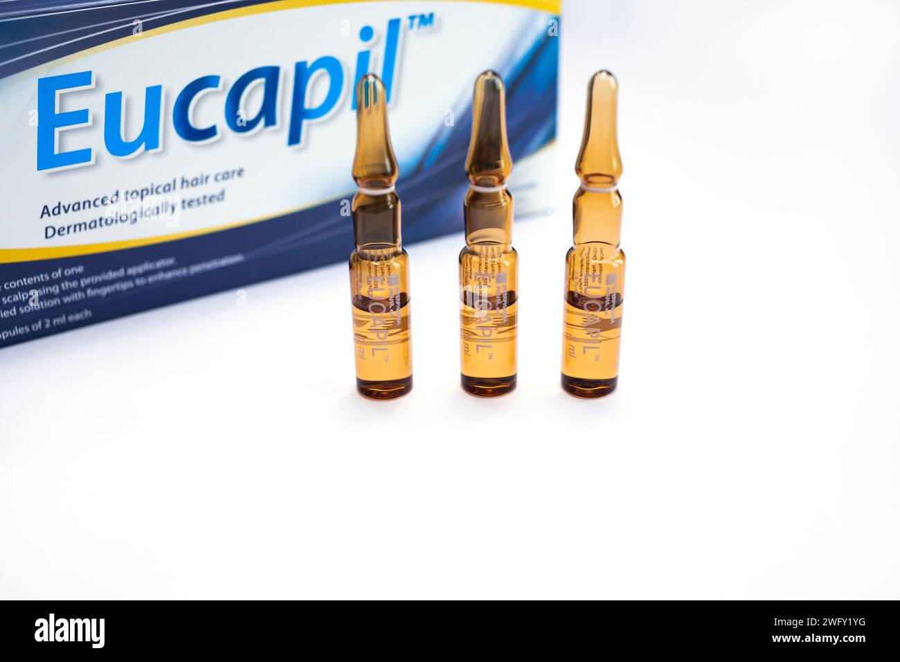 Eucapil-Box, Fluridil-Lotion im Satz von Ampullen, kosmetisches Mittel zur topischen Anwendung bei androgenetischer Alopezie, Haarausfall auf blauem Hintergrund. Nahaufnahme Stockfoto