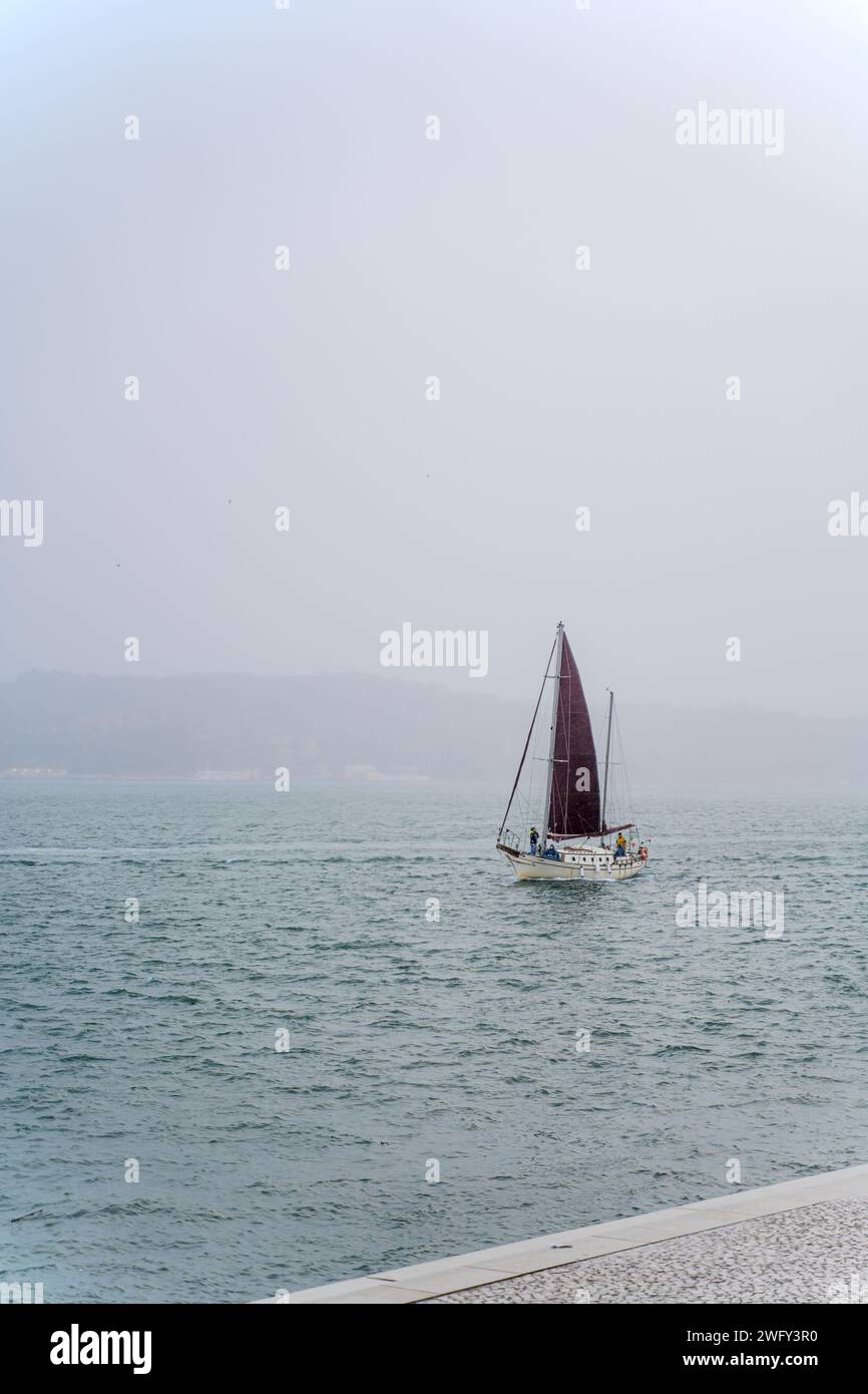Ein Solo-Segelboot auf Meer und nebeligem Hintergrund. Stockfoto