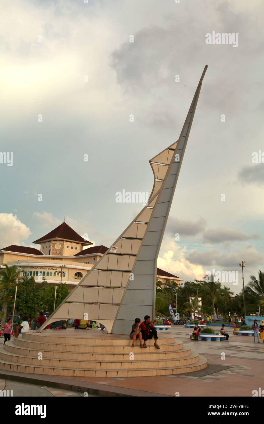 Die Menschen haben Freizeit an und um eines der beiden identischen Denkmäler, die als Eingangstor zum Pantai Losari (Losari Beach, ein beliebtes Erholungsziel für Sonnenuntergänge in Makassar City, Süd-Sulawesi, Indonesien. Stockfoto