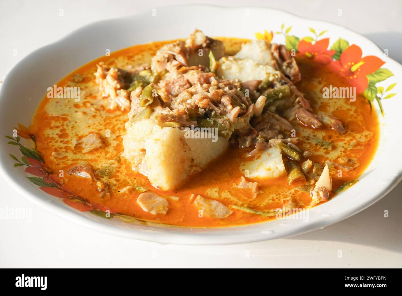 Lontong Sayur oder Gemüsereis Kuchen ist ein typisches indonesisches Essen auf einer weißen Platte mit isoliertem weißem Hintergrund Stockfoto