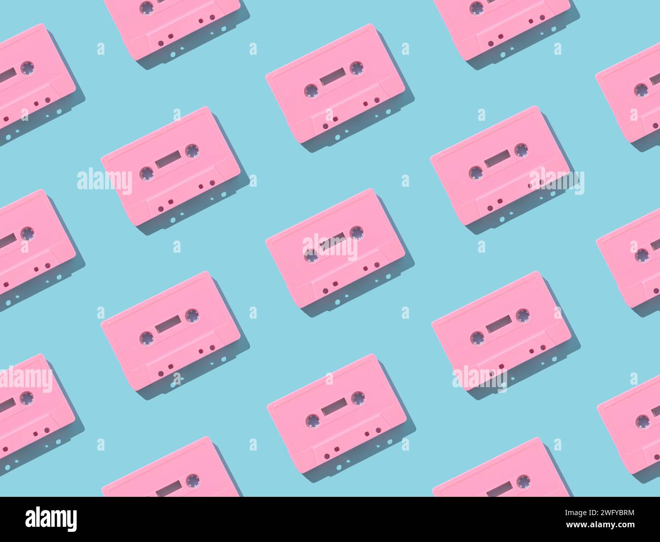 Muster mit rosafarbenen Retro-Audiokassettenbändern auf hellblauem Hintergrund. Kreatives Konzept der Retro-Technologie. Ästhetik der 80er Jahre. Vintage-Audio Stockfoto