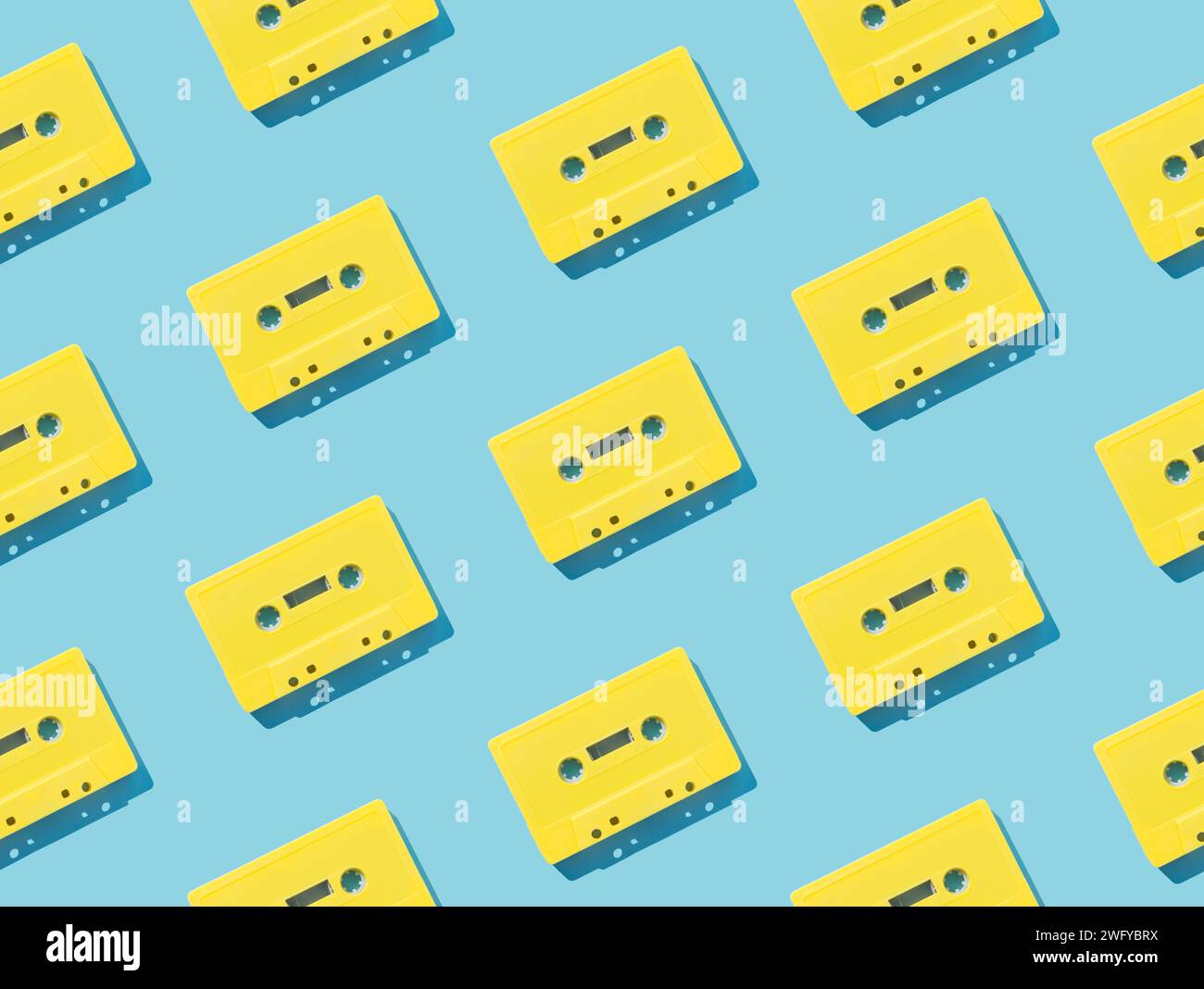 Muster mit gelben Retro-Audiokassetten auf hellblauem Hintergrund. Kreatives Konzept der Retro-Technologie. Ästhetik der 80er Jahre. Vintage-Audio Stockfoto