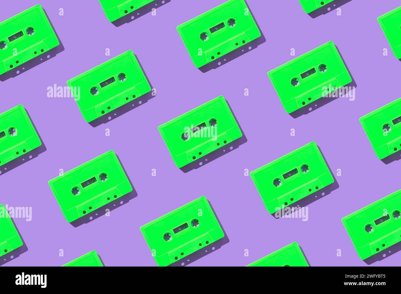 Muster mit grünen Retro-Audiokassetten auf violettem Hintergrund. Kreatives Konzept der Retro-Technologie. Ästhetik der 80er Jahre. Vintage-Audio Stockfoto