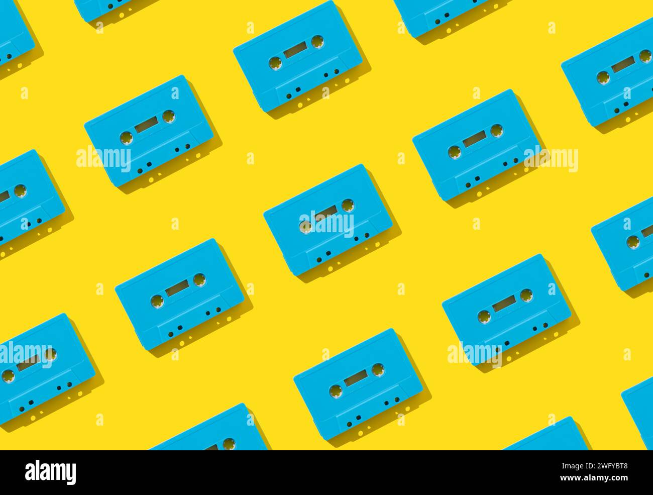 Muster mit blauen Retro-Audiokassetten auf gelbem Hintergrund. Kreatives Konzept der Retro-Technologie. Ästhetik der 80er Jahre. Vintage-Audio Stockfoto