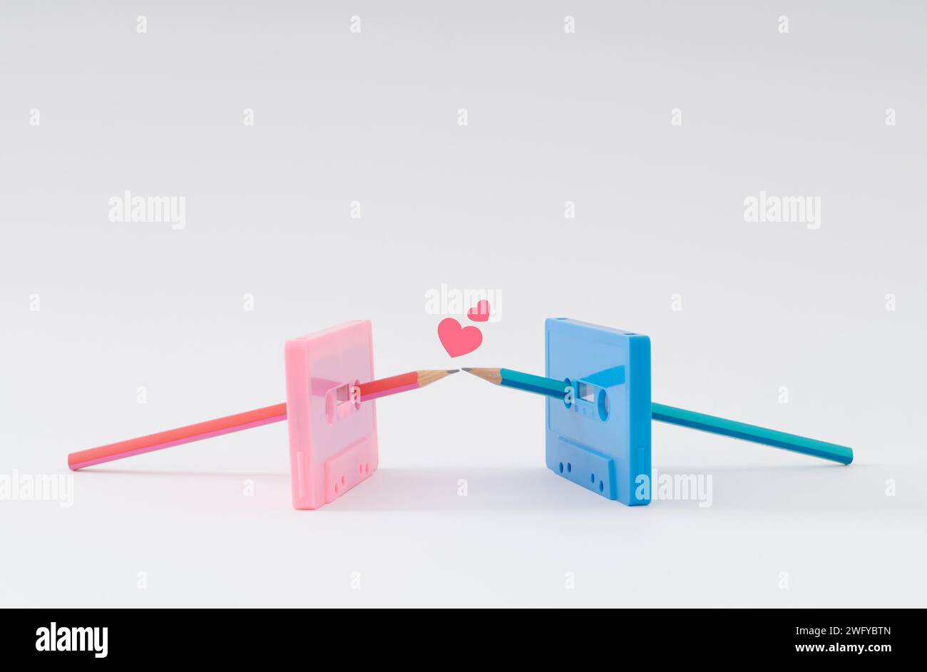 Du bist der Bleistift für mein Kassettenband. Alte pinkfarbene und blaue Tonkassetten und Bleistifte küssen sich. Minimales Liebeskonzept. Kreative Idee für Kassetten. Stockfoto