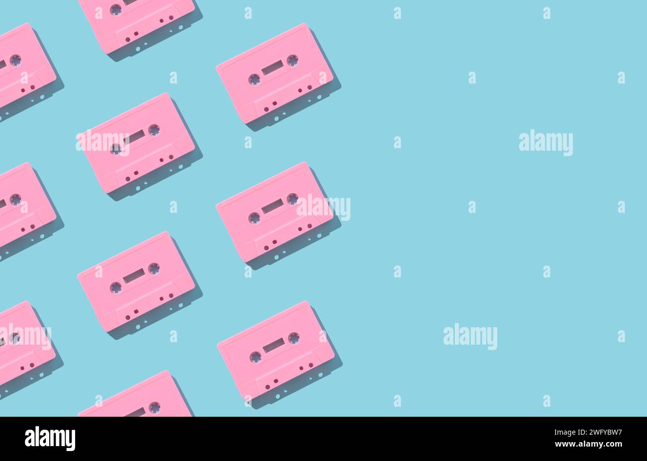 Muster mit rosafarbenen Retro-Audiokassettenbändern auf hellblauem Hintergrund. Kreatives Konzept der Retro-Technologie. Ästhetik der 80er Jahre. Vintage-Audio Stockfoto