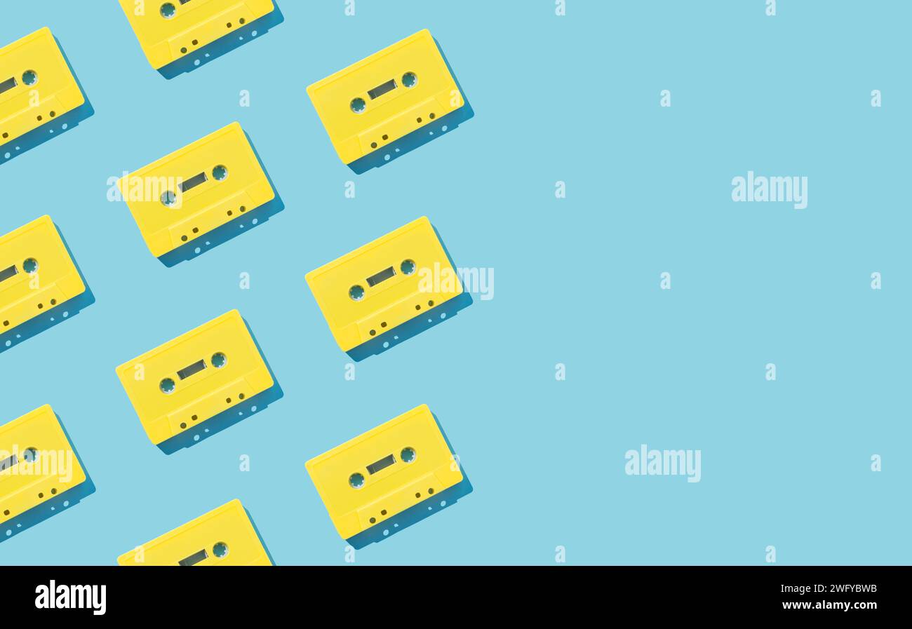 Muster mit gelben Retro-Audiokassetten auf hellblauem Hintergrund. Kreatives Konzept der Retro-Technologie. Ästhetik der 80er Jahre. Vintage-Audio Stockfoto