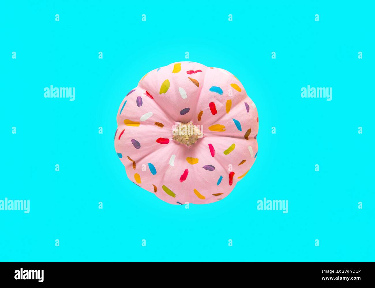 Kürbis bemalt wie ein rosafarbener Donut mit Streuseln Stockfoto