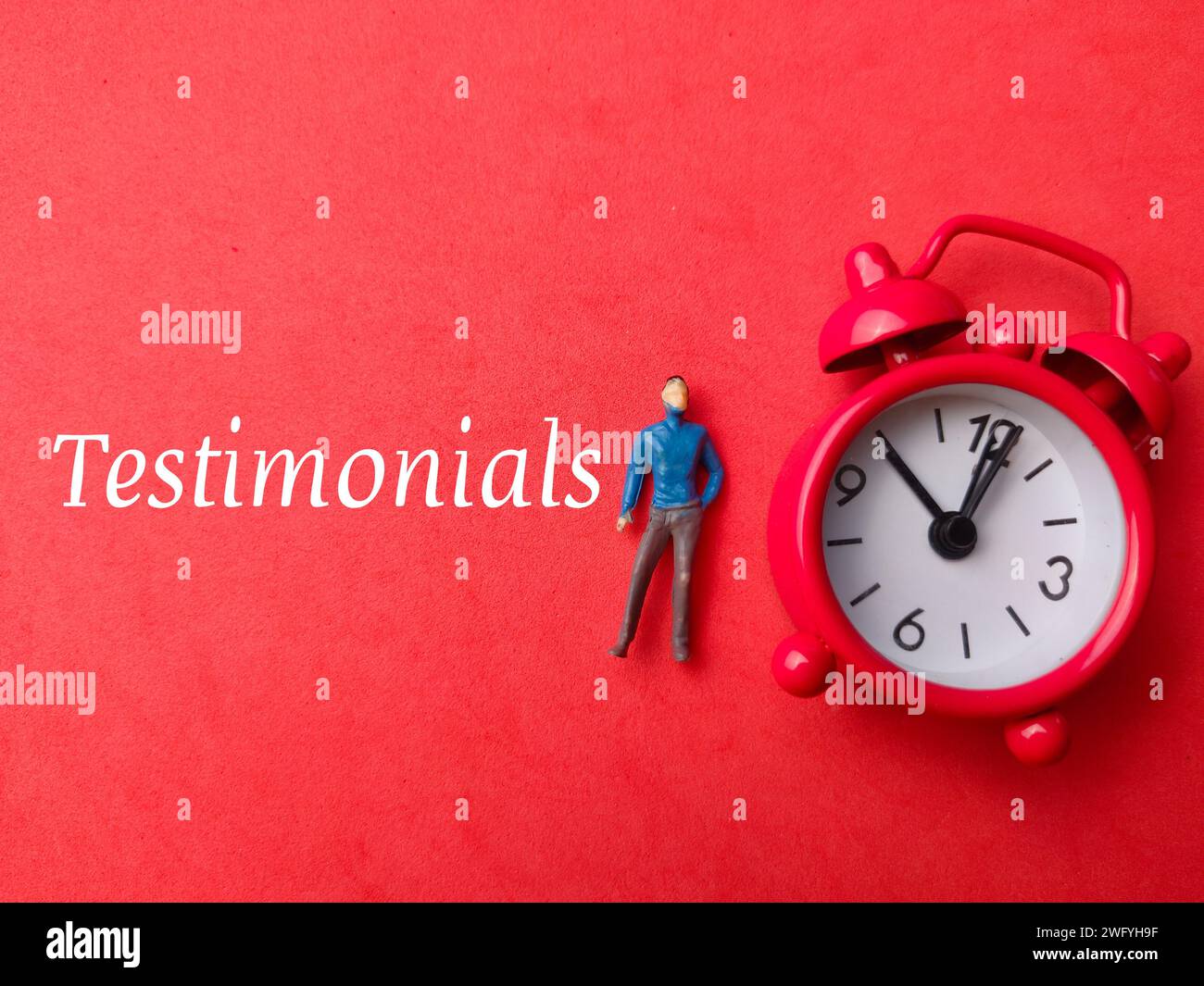 Draufsicht Miniaturmenschen und Uhr mit Text Testimomials auf rotem Hintergrund. Stockfoto