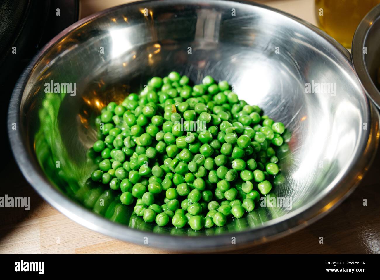 Eine Schüssel mit leuchtenden grünen Erbsen, die gesunde Ernährung und frische Produkte widerspiegeln, eine wichtige Zutat für nahrhafte Mahlzeiten. Stockfoto