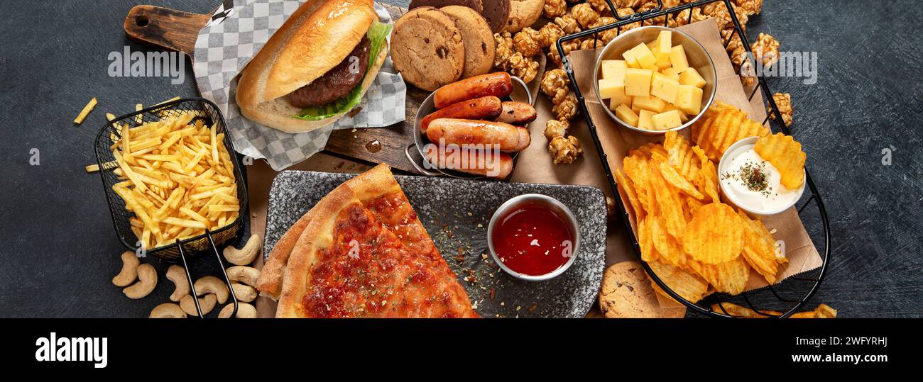 Fastfood auf dunklem Hintergrund. Junk Food für Herz und Haut. TRANS FAT-Konzept. Draufsicht, Banner Stockfoto