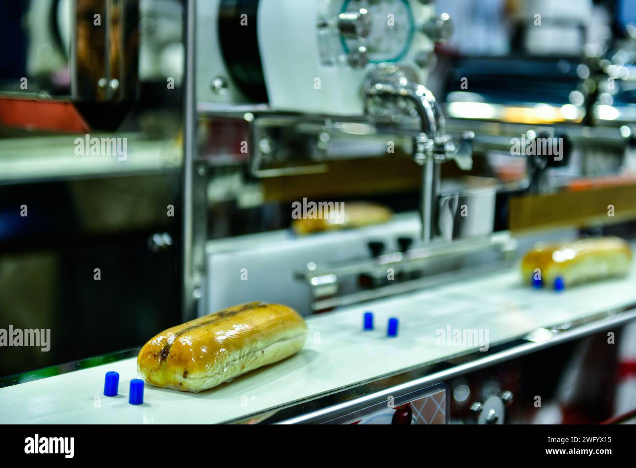 Produktionslinie für automatische Hamburger-Brötchen an Förderbandmaschinen in der Fabrik, industrielle Nahrungsmittelproduktion. Stockfoto