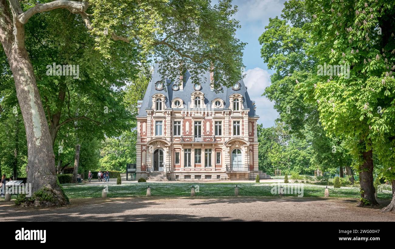 Ein geräumiges Backsteingebäude inmitten üppiger Bäume mit gepflegtem Rasen Stockfoto