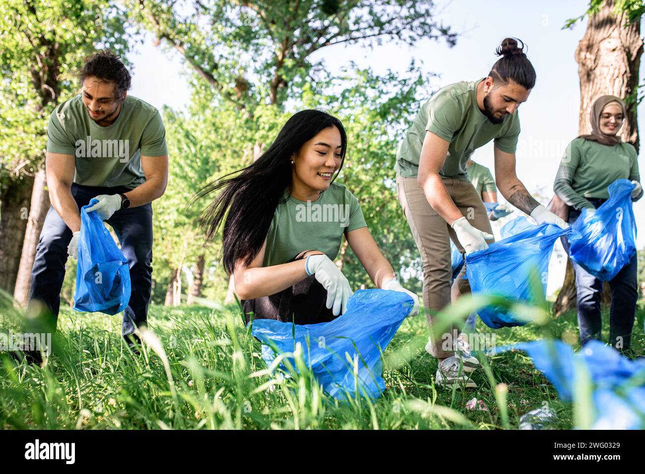 Multiethnische Gruppe von Freiwilligen mit Müllsäcken, die den Stadtpark reinigen. Stockfoto