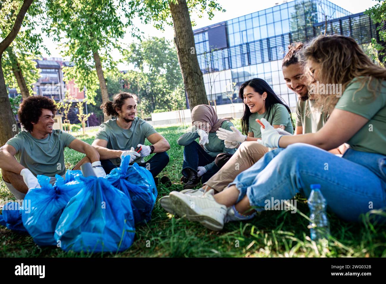 Multiethnische Gruppe von Freiwilligen, die sich nach der Reinigung des Stadtparks ausruhen. Stockfoto