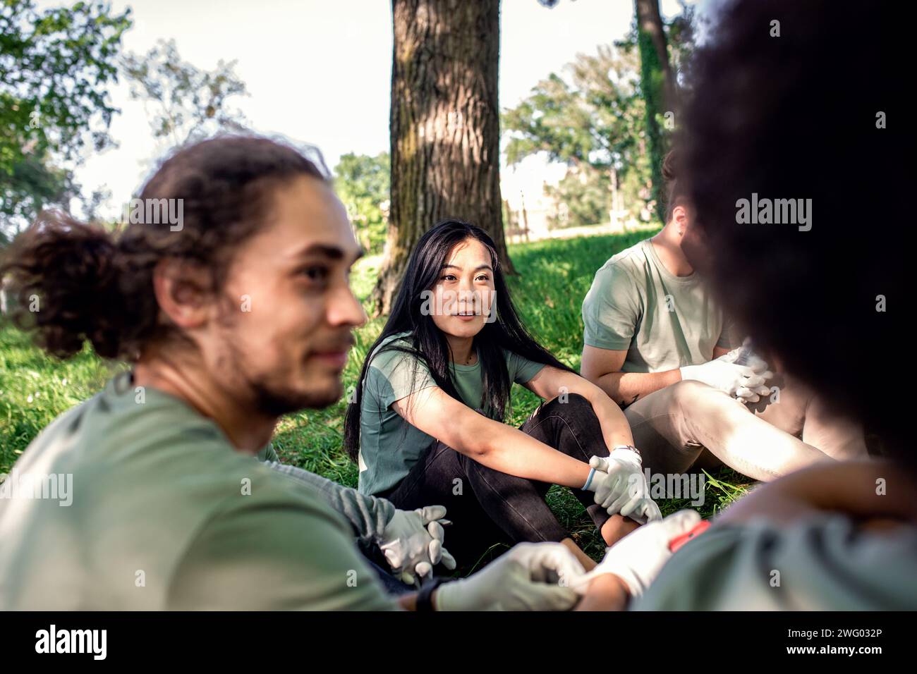 Multiethnische Gruppe von Freiwilligen, die sich nach der Reinigung des Stadtparks ausruhen. Stockfoto