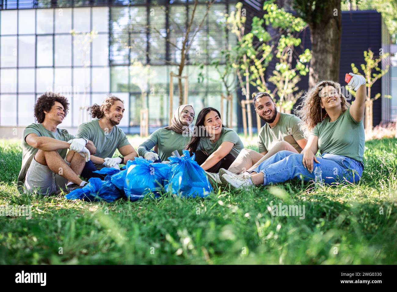 Multiethnische Gruppe von Freiwilligen, die sich nach der Reinigung des Stadtparks ausruhen. Stockfoto