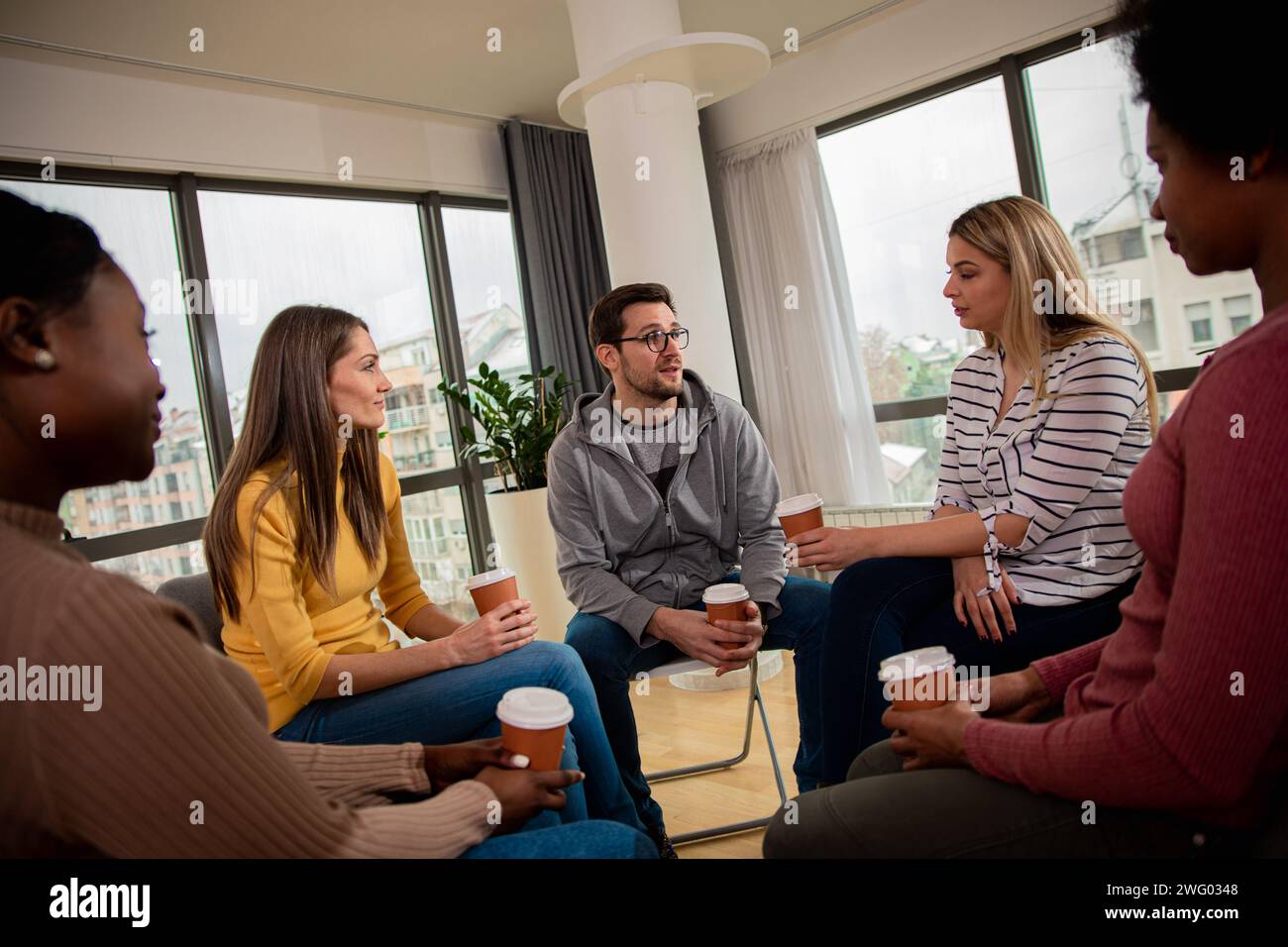 Verschiedene Gruppen von Personen, die in Gruppentherapiesitzungen im Kreis sitzen. Stockfoto