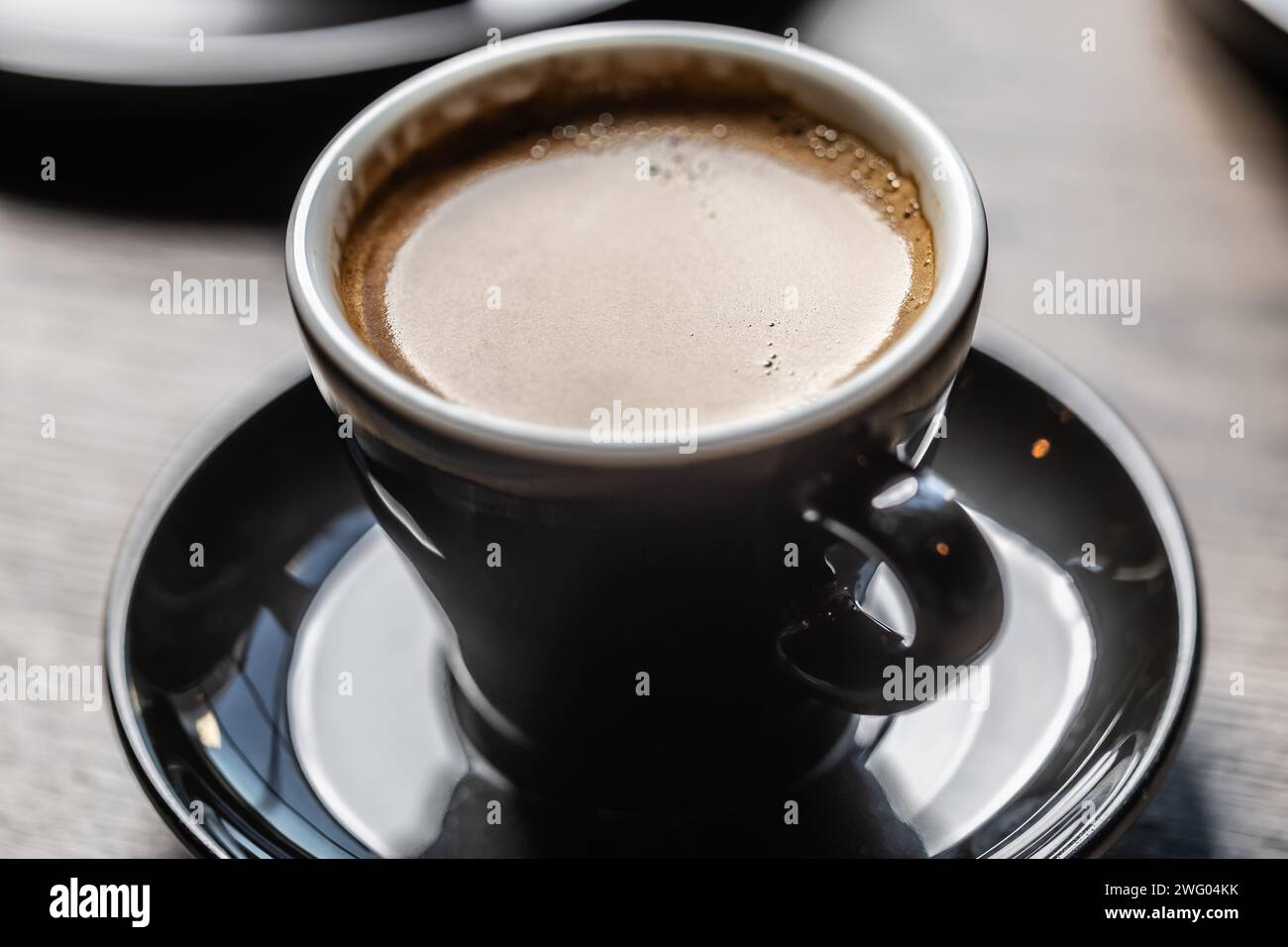 Traditioneller Espresso in einer schwarzen Tasse auf einem Tisch in einem Café. Stockfoto