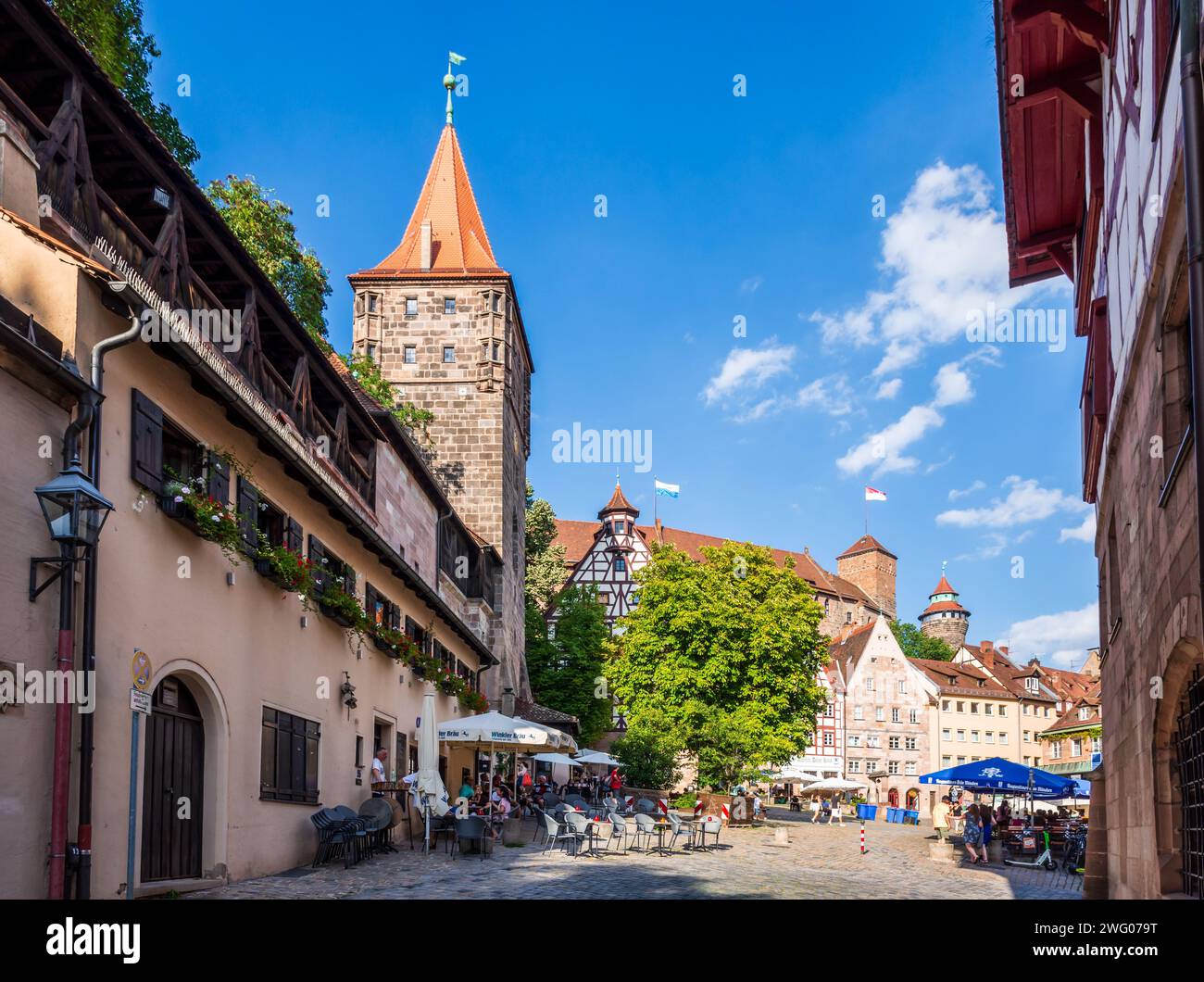 Blick auf den Tiergärtnertorturm in Nürnberg, ein befestigter Turm in der mittelalterlichen Stadt, mit Straßencafés auf dem Tiergärtnertorplatz. Stockfoto