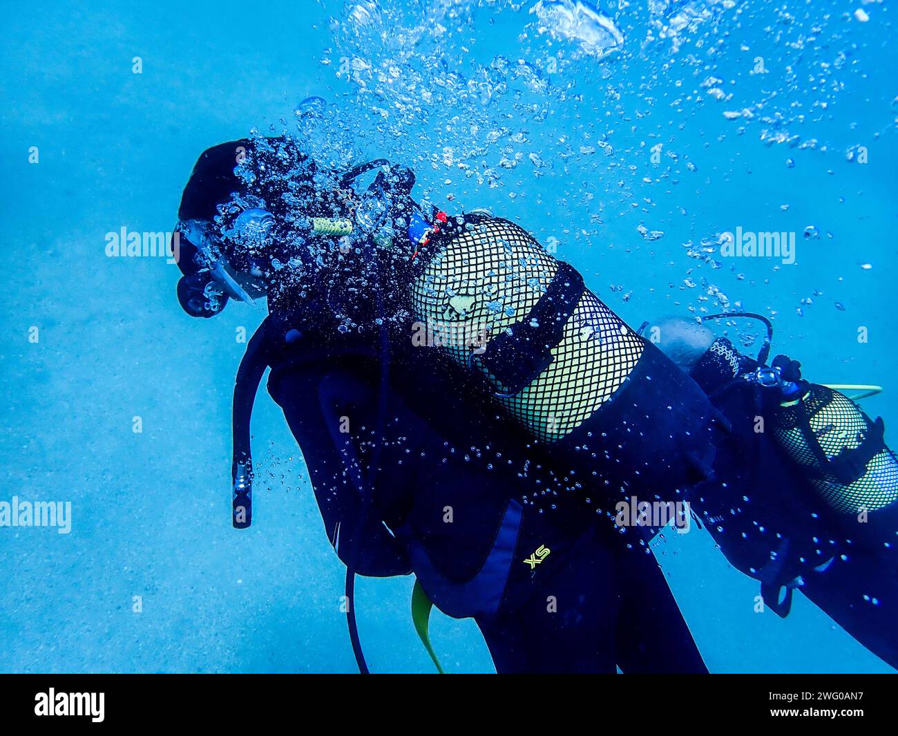 Taucher tauchten in Lanzarotes azurblauen Tiefen ein, umgeben von tanzenden Luftblasen in einer Unterwasser-Symphonie Stockfoto