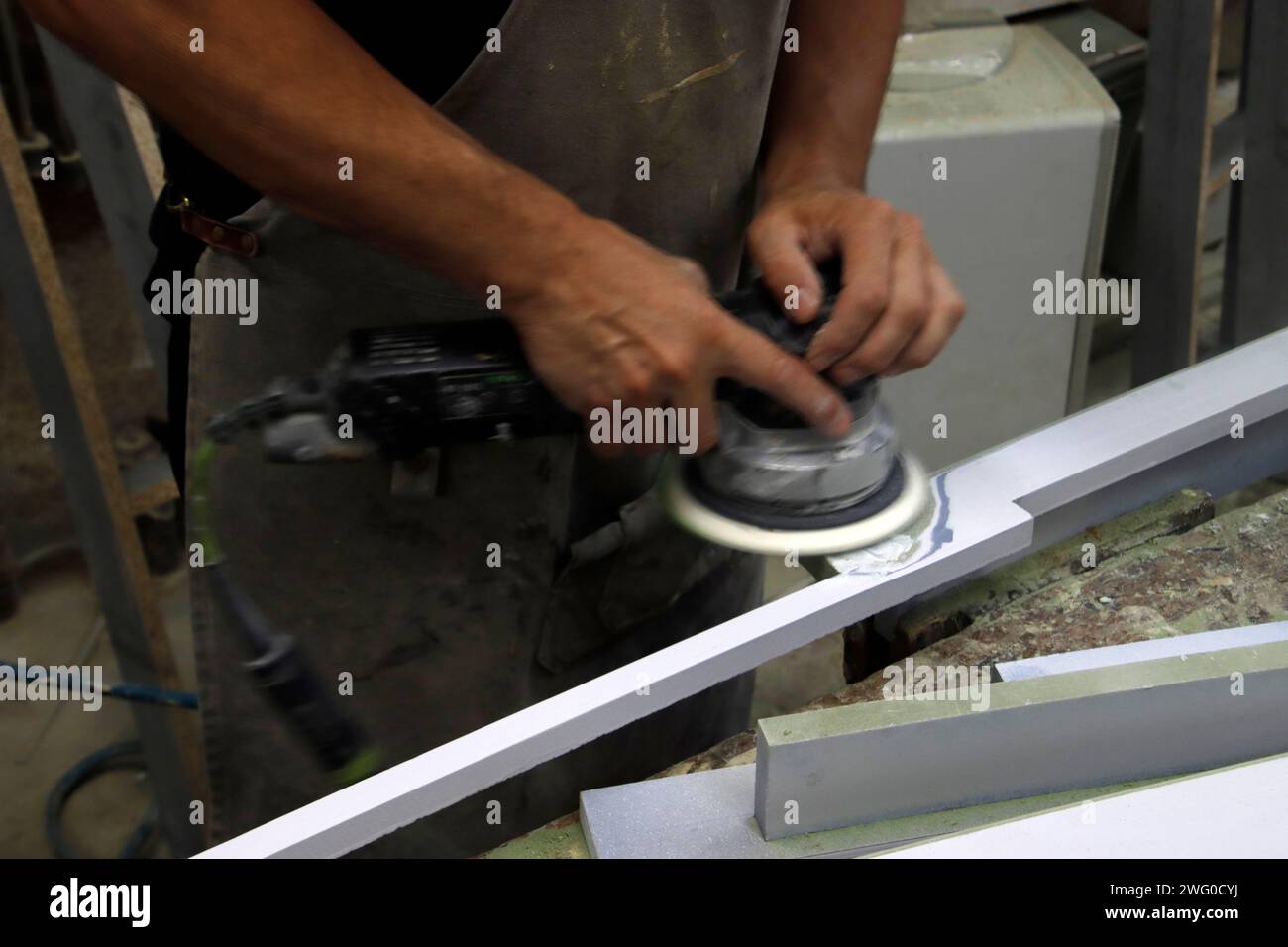 Ein Arbeiter, der eine Schleifmaschine auf einer Betonoberfläche bedient Stockfoto