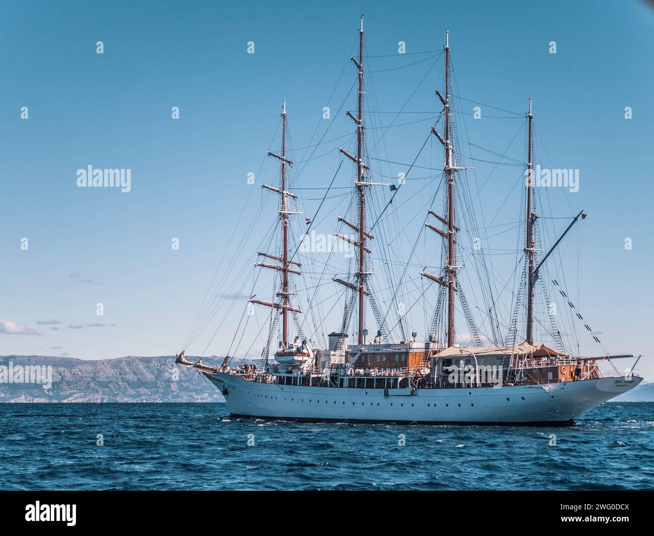 Vier Masten, weißes Segelboot, rotes Dach, segelt auf einem riesigen blauen Ozean unter einem klaren blauen Himmel, was die Aufmerksamkeit des Bildes erregt. Stockfoto