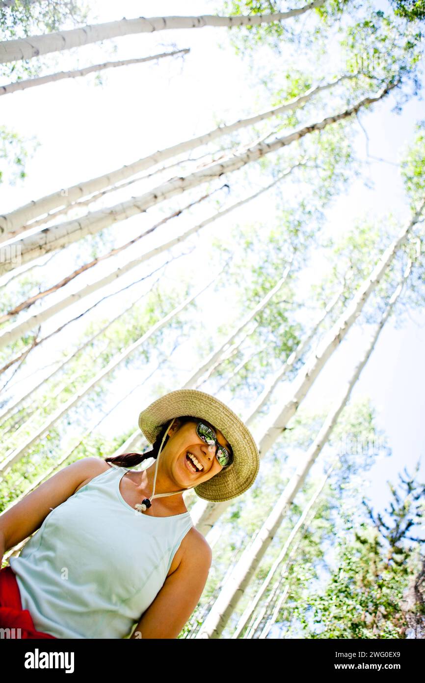 Eine Frau steht in einem Wald aus Aspen. Stockfoto