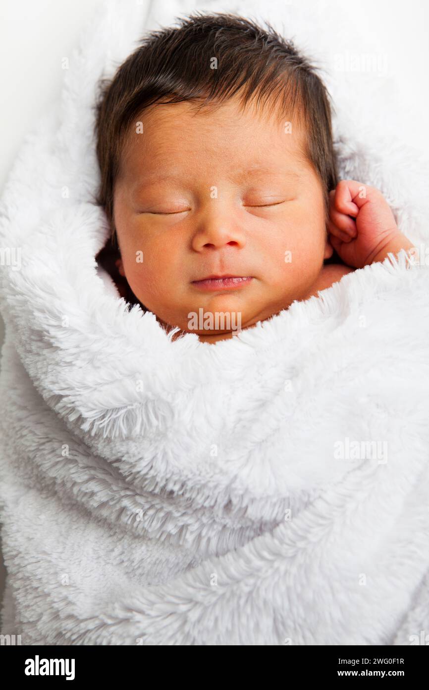 Ein 10 Tage altes japanisches amerikanisches Kleinkind schläft in einer weißen, flauschigen Decke. Stockfoto