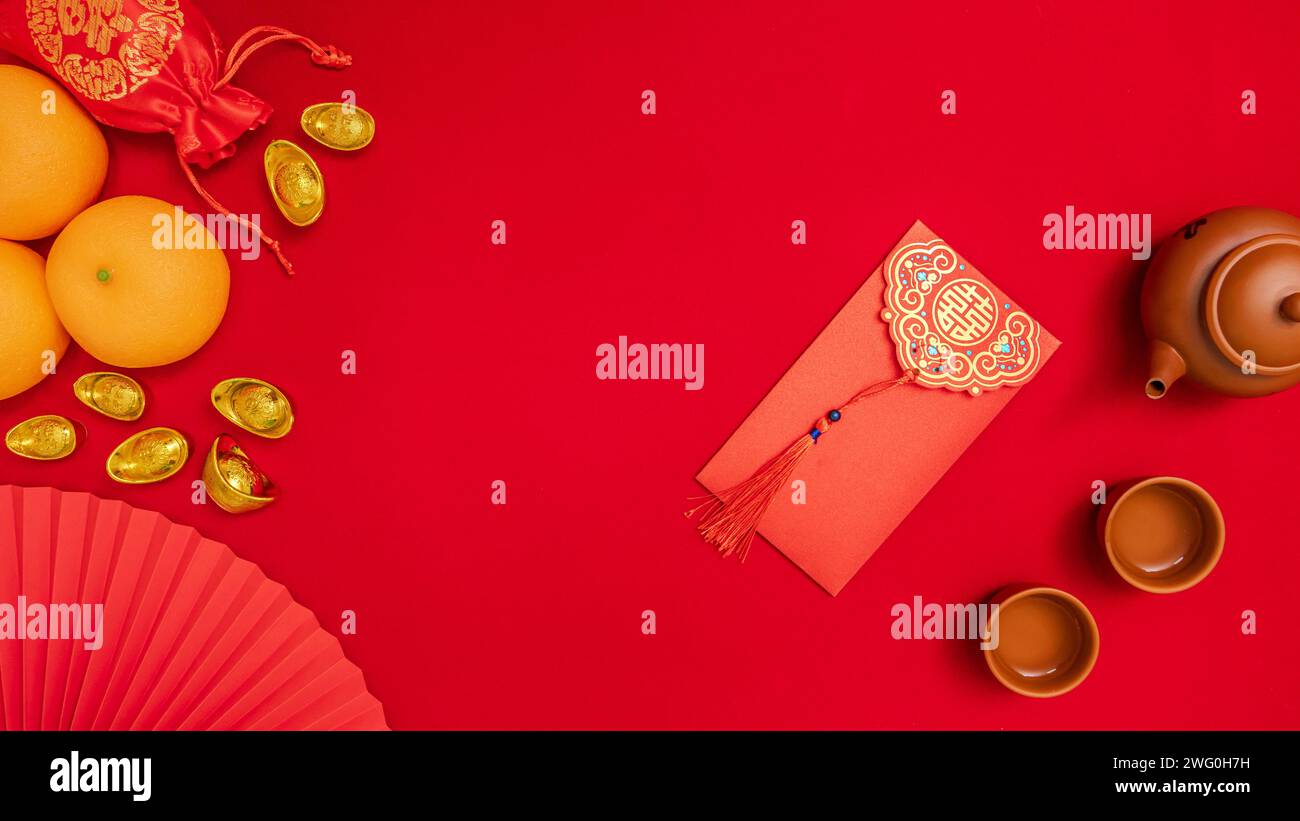 Chinesisches Mondneujahrshintergrund, rotes Thema. Flache Seidentasche mit antikem Goldstab, Orange, Papierhandfächer, Teekanne, Teetasse, roter Umschlag, ang Pow Stockfoto