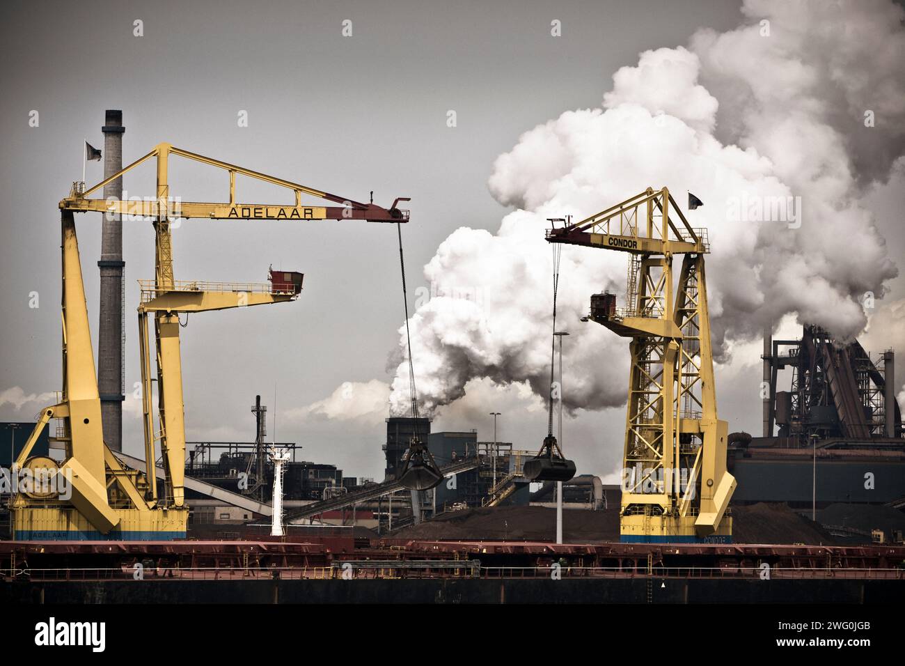 Zwei Kräne laden Kohle von einem Schiff ab, um die Hoogovens in Ijmuiden, Niederlande, zu betanken. Stockfoto