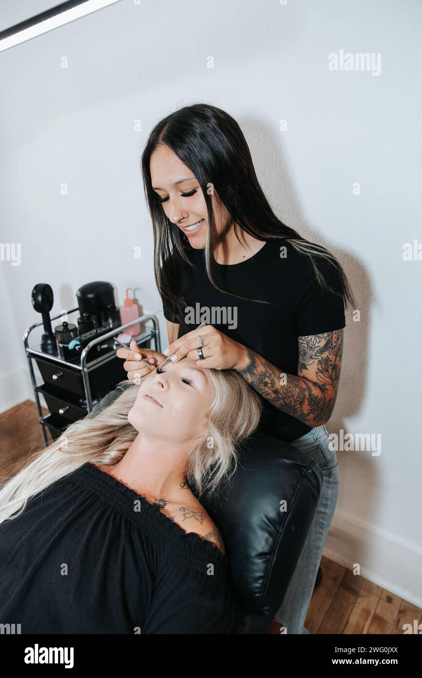 Stilvolles Mädchen wendet Wimpern an, die Schönheit des Kunden in der Entspannung Stockfoto