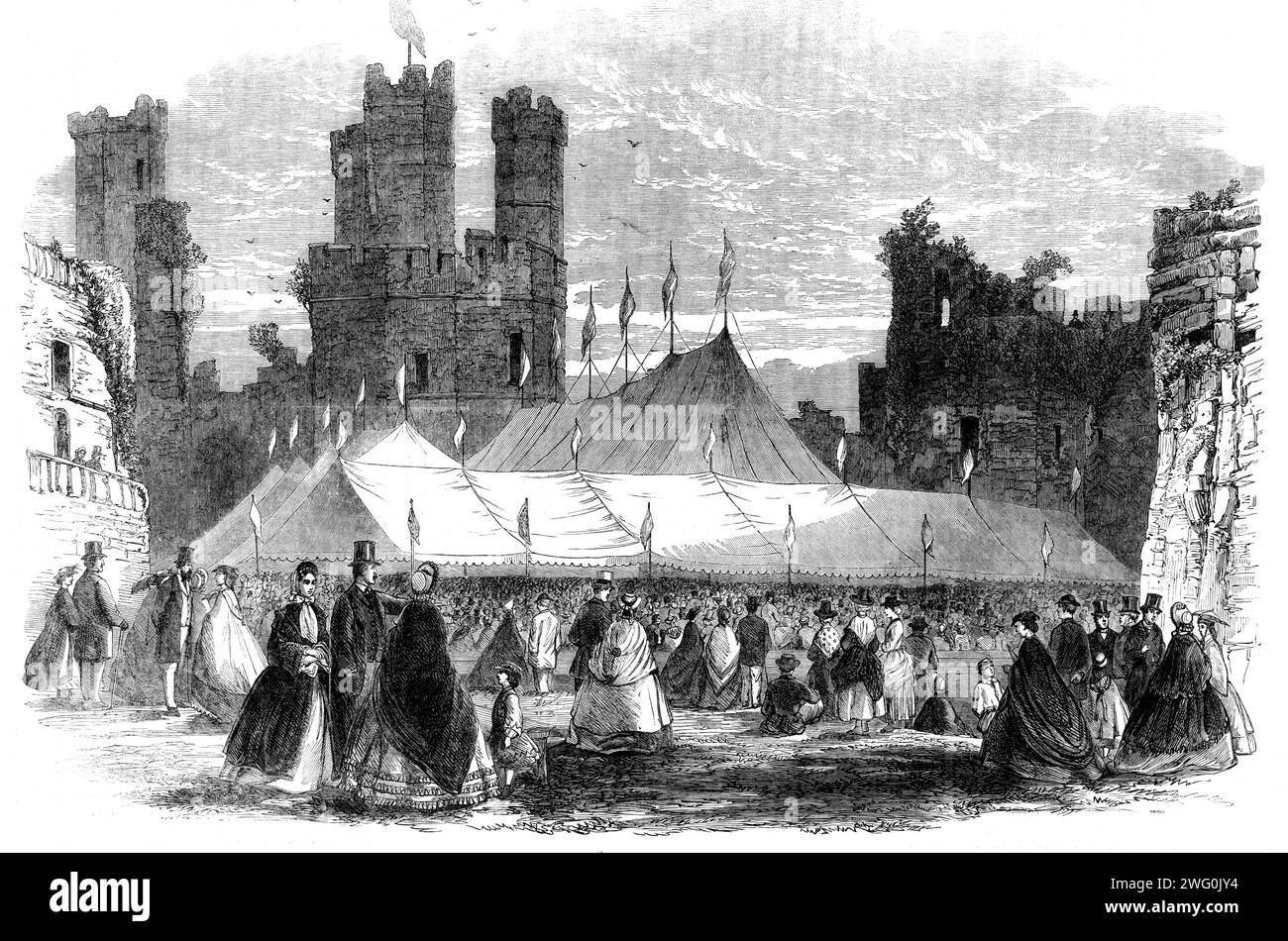 Grand National Eisteddfod in Carnarvon Castle, [Wales], 1862. Auf dem großen Nationalkongress der kambrischen Bards, Musikanten, Historiker und Handwerker... waren es durchschnittlich 13.000 Besucher pro Tag. Das Festzelt, in dem sich die Gesellschaft versammelt hatte, war so angelegt, dass es 7000 bis 8000 Personen vollen Komfort gewährleistete... das Dachtuch des Pavillons wurde von verschiedenen Ornamenten gekrönt; und vom Dachbaum, wenn ja, können wir die obersten, schwimmenden Fahnen in verschiedenen Größen und Designs nennen. Der Architekt dieses Festzimmers war Mr. D. Thomas. Unter den Wettbewerbsobjekten waren Waliser dwelli Stockfoto