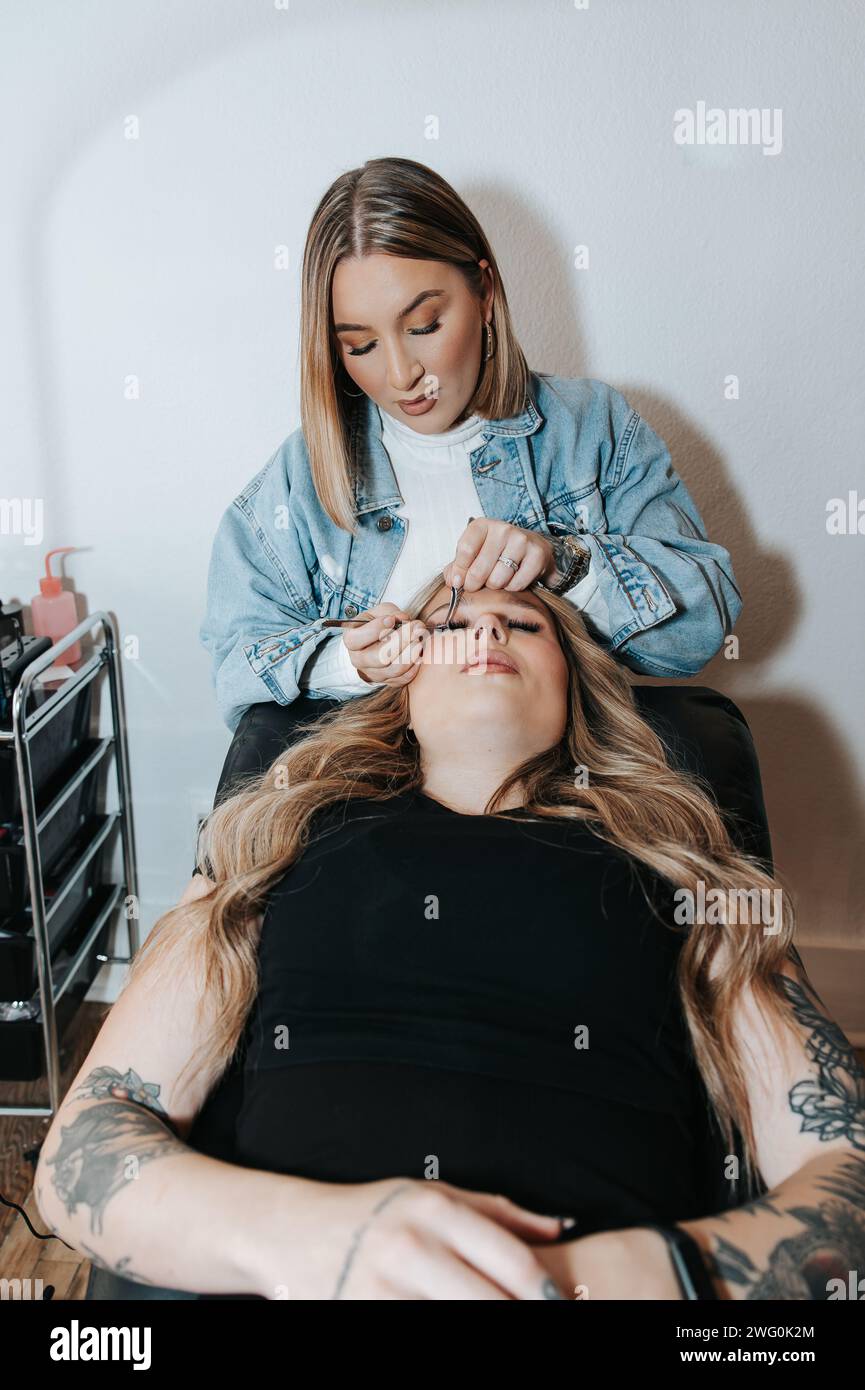 Mädchen mit kurzen blonden Haaren wendet Wimpern auf einen Kunden an, der sich hinlegt Stockfoto