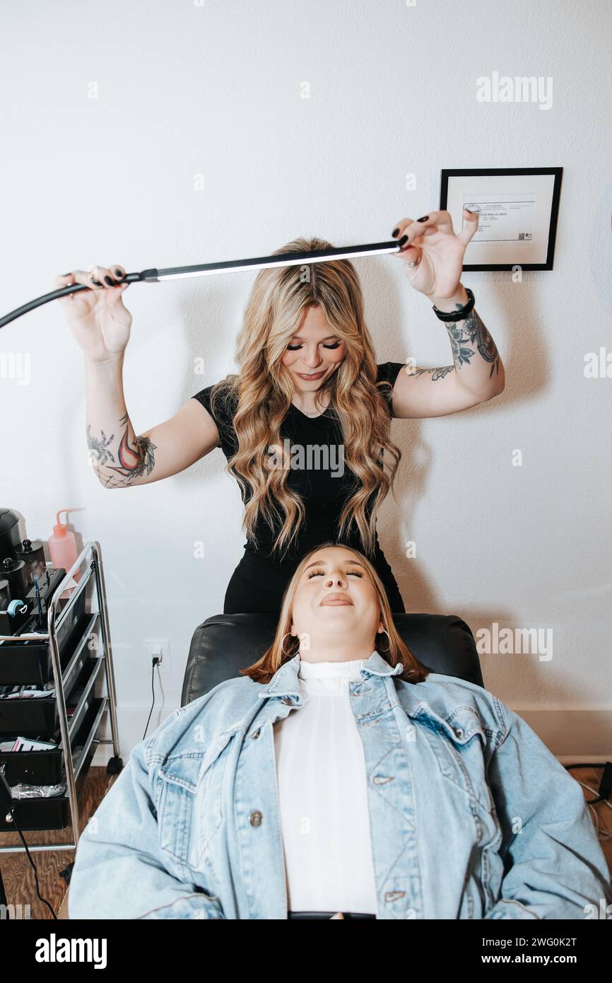 Blondes Mädchen in schwarzem Kleid, Lichter oben, Vorbereitung auf Wimpernklient Stockfoto
