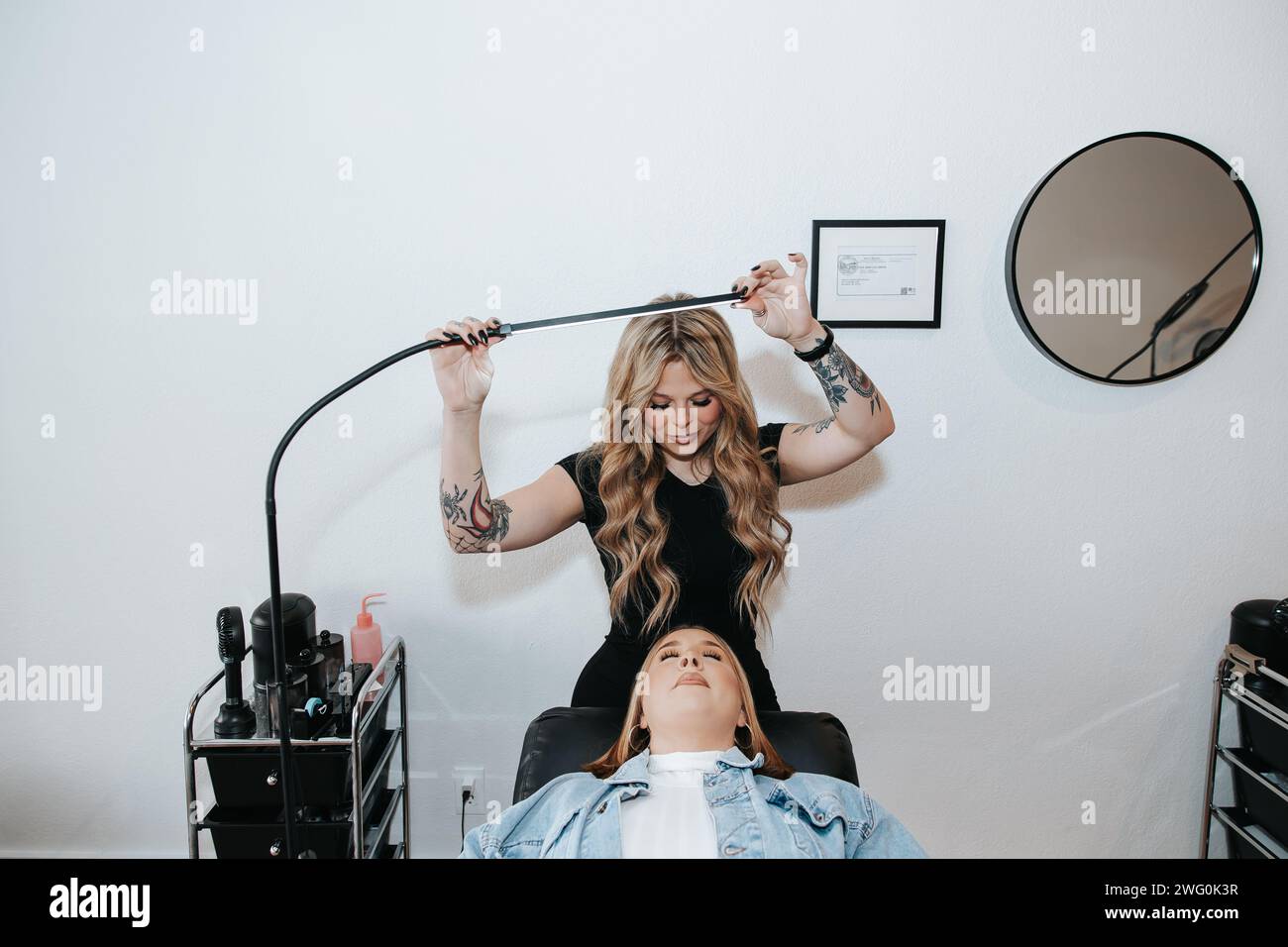 Blondes Mädchen in schwarzem Kleid, Lichter oben, Vorbereitung auf Wimpernklient Stockfoto