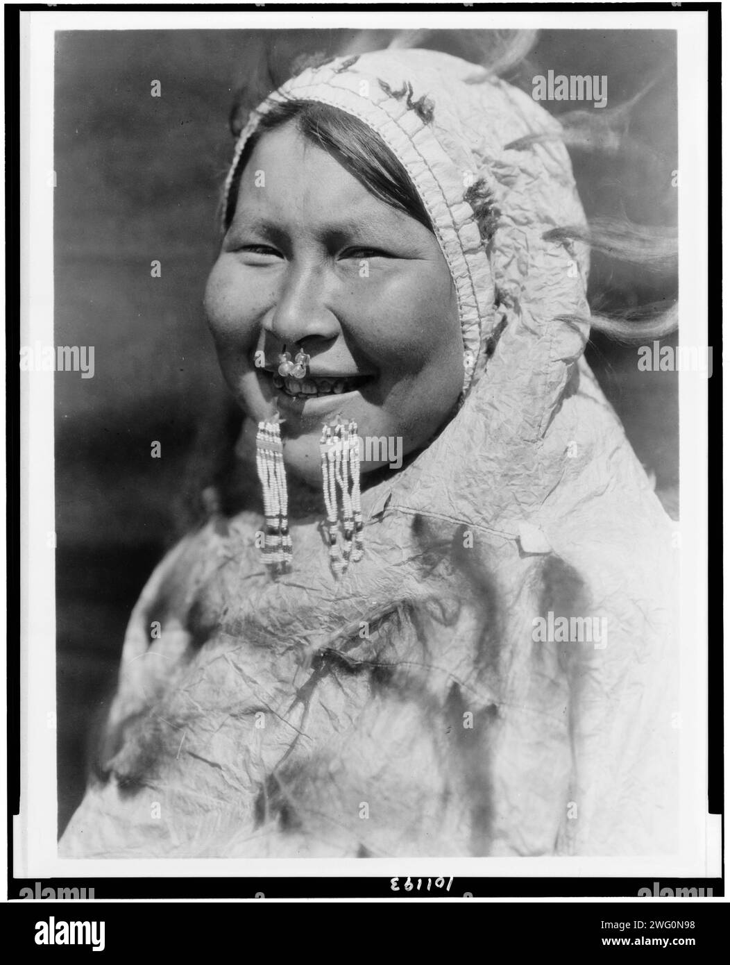 U?iyaku-Nunivak, 1929. Kopf-und-Schultern-Porträt der Eskimo-Frau aus der Arktis mit Nasenring und Labret. Ihr Kapuzenparka ist aus Darmpergament. Stockfoto